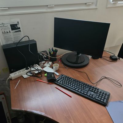 un bureau sur lequel se trouvent un clavier, un écran, une souris et d'autres objets