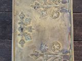 une boîte en métal ornée d'un motif, posée sur une table en bois