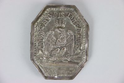 une vieille assiette en argent sur laquelle est représenté un aigle