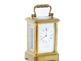 a small gold clock with a handle on a white background