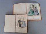 trois livres sur lesquels figurent des dessins de femmes en robe, posés sur une table