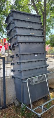 une pile de récipients en plastique posée par terre près d'une clôture