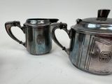 two silverplated teapots with lids and handles on a white surface