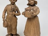 trois figurines représentant des enfants tenant des paniers de fleurs