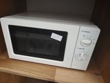 un micro-ondes blanc posé sur une étagère en bois dans un placard