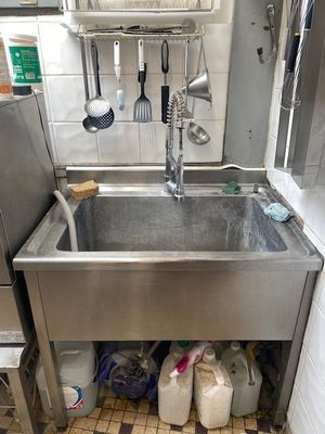 un évier de cuisine avec de nombreux ustensiles posés sur le plan de travail