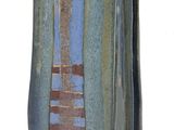 un vase bleu et brun posé sur une surface blanche