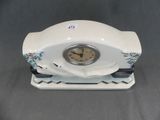 a white clock sitting on top of a white stand
