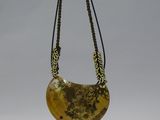 necklace made of yellow jade with gold leaf decoration on a black metal stand