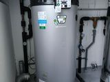 a water heater in the corner of a room with pipes