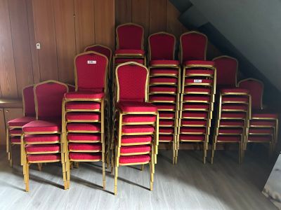 des rangées de chaises rouges dans une pièce aux murs lambrissés