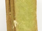 an old book sitting on top of a white table next to a white wall