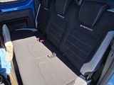 a woman standing in the back seat of a blue van