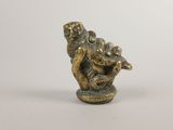 figurine en laiton représentant un singe tenant un poisson, sur fond blanc