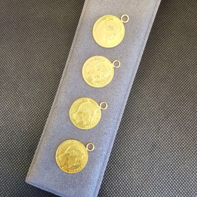 trois pièces d'or sont posées sur un tissu bleu, retenues par un cordon argenté