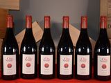 six bouteilles de vin rouge sont alignées sur une table