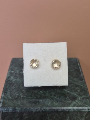 un gros plan sur une paire de boucles d'oreilles en or posées sur un bloc de marbre