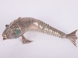 a silver fish that is laying down on a white surface
