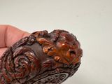 a hand holding a piece of wood with carvings on it