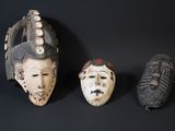 three masks on a black surface with a black background