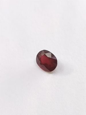 une pierre de grenat rouge posée sur une surface blanche
