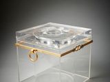 a clear box with a gold handle on a grey background