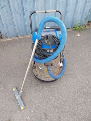 un aspirateur bleu posé par terre à côté d'un mur bleu