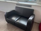 un canapé en cuir noir placé devant une fenêtre dans un salon