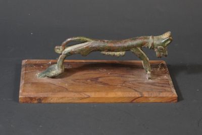 bronze statue of a cat on a wooden base on a black background