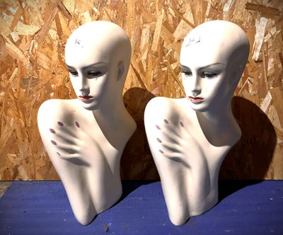 deux têtes de mannequin blanches posées sur une surface bleue