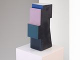 sculpture made of black, pink, blue and white blocks on a white pedestal