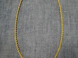 un collier à chaîne en or posé sur un tissu gris