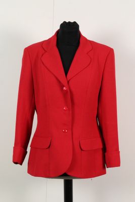 La veste rouge est présentée sur un mannequin posé sur un socle noir.