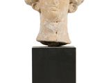 une tête de femme antique posée sur un socle noir