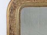 a mirror with a gold frame on a white wall