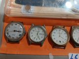 three watches on display in a display case with a plane in the background