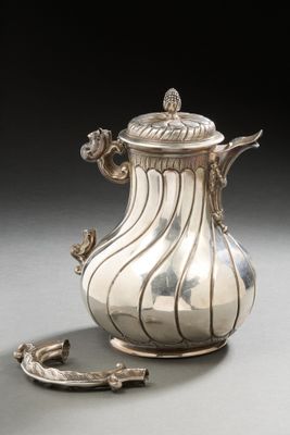 an antique silver coffee pot with a spoon on a table