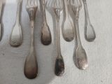 de nombreuses cuillères et fourchettes en argent posées sur une table