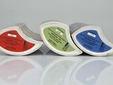 three rolls of colored tape sitting next to each other on top of a white surface