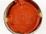 a red paint in a metal container on a white surface