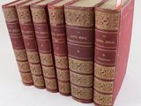six vieux livres sont alignés sur une surface blanche