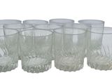 six verres transparents sont alignés sur une surface blanche