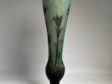 a green vase with a bird on it on a table