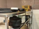 many plates and pans on a metal shelf in a kitchen