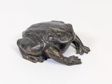 statue of a frog sitting on a white surface
