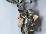 a statue of an angel holding a candelier with birds on it