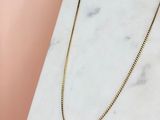 un collier à chaîne en or posé sur une surface en marbre