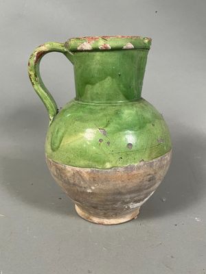 a green vase with a handle sitting on a table