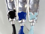 trois tubes de dentifrice posés sur une surface blanche