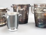 four silver vases and two silver cups on a table